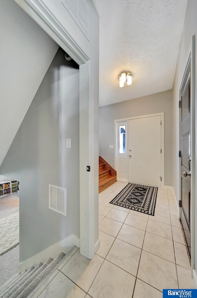 foyer featuring visible vents, a textured ceiling, and light tile patterned flooring