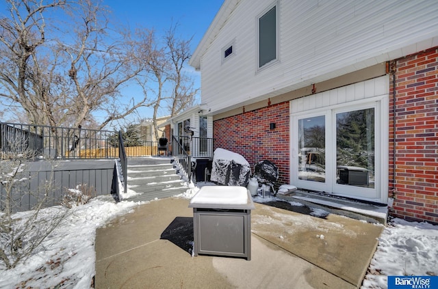 view of snowy exterior with brick siding