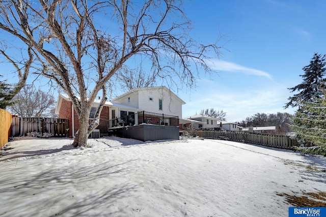 snow covered back of property featuring fence private yard and brick siding