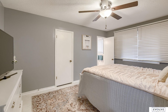 bedroom with a textured ceiling, ceiling fan, light tile patterned flooring, and baseboards