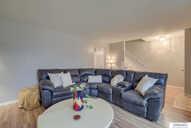 living area with baseboards, stairway, and light wood finished floors