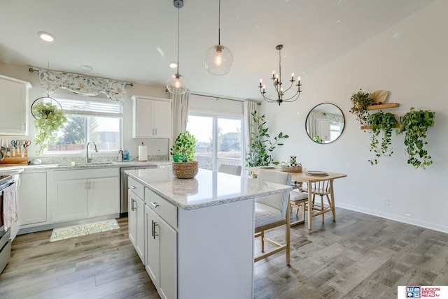 kitchen featuring light wood finished floors, a kitchen island, a sink, and a wealth of natural light