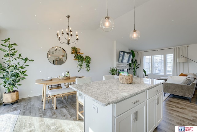 kitchen with a center island, a notable chandelier, light wood-style flooring, open floor plan, and white cabinets