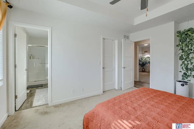 bedroom with connected bathroom, visible vents, baseboards, a tray ceiling, and carpet