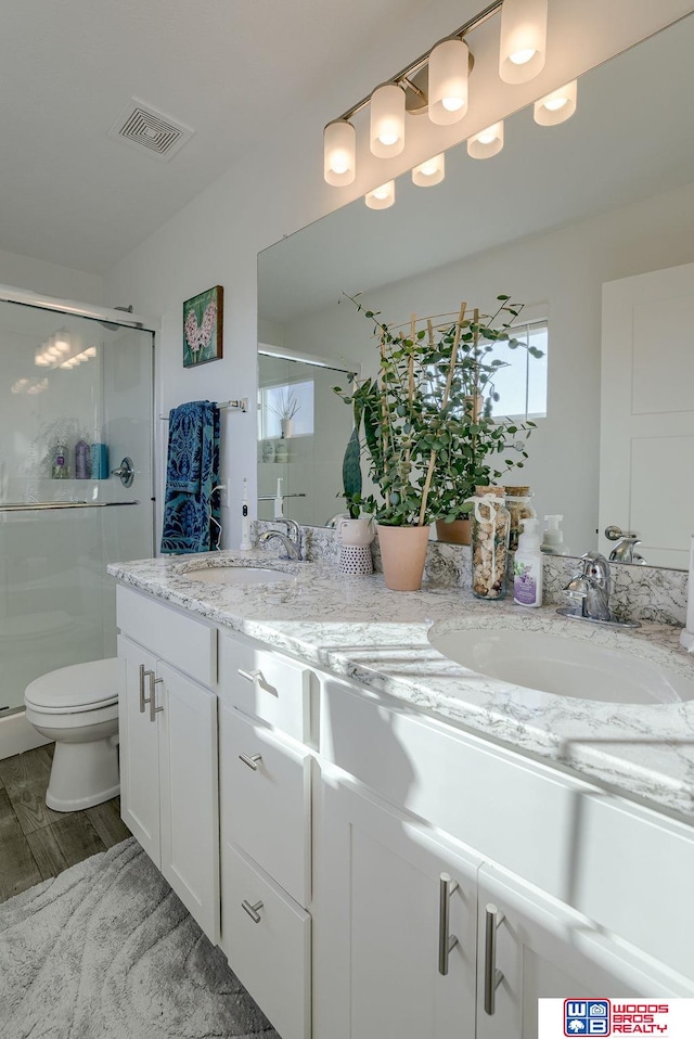 bathroom featuring double vanity, a stall shower, a sink, and visible vents