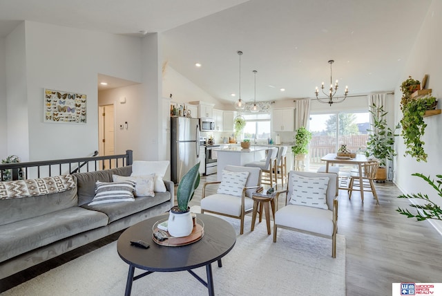 living area featuring a chandelier, high vaulted ceiling, light wood finished floors, and recessed lighting