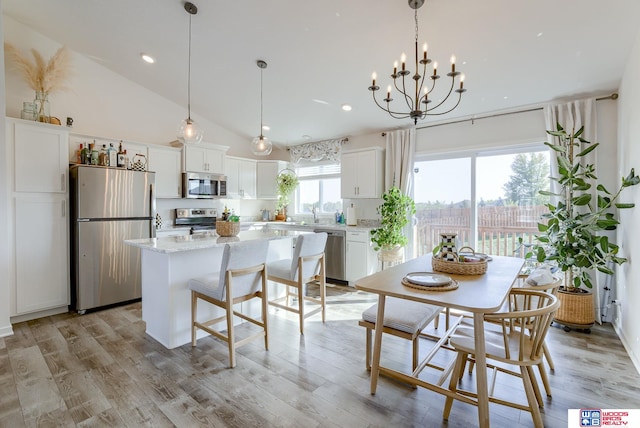 kitchen featuring a center island, pendant lighting, light wood finished floors, stainless steel appliances, and white cabinets