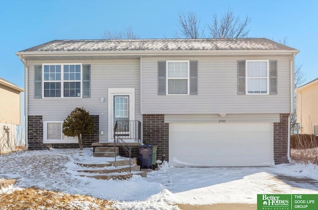 split foyer home featuring a garage, driveway, and brick siding