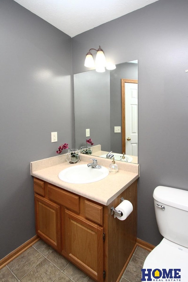 half bathroom with tile patterned floors, vanity, toilet, and baseboards