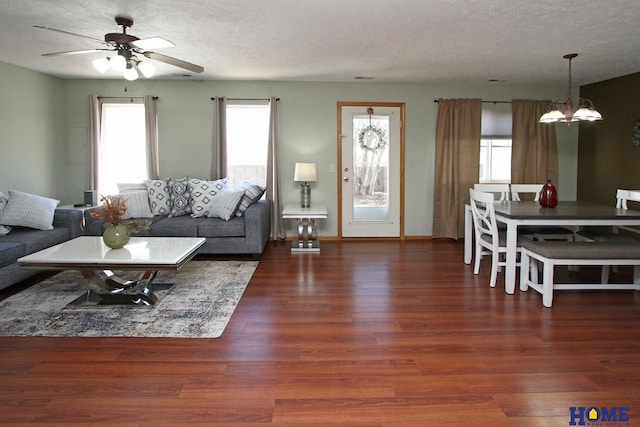 living room with a textured ceiling, ceiling fan with notable chandelier, wood finished floors, and baseboards