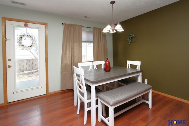 dining space featuring a chandelier, visible vents, baseboards, and wood finished floors