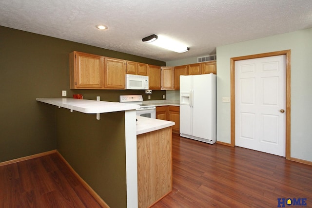 kitchen with a peninsula, white appliances, light countertops, and visible vents