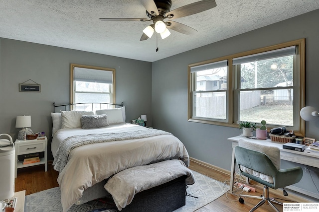 bedroom featuring a textured ceiling, wood finished floors, a ceiling fan, and baseboards