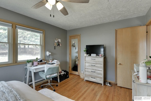 bedroom featuring light wood finished floors, ceiling fan, and a textured ceiling