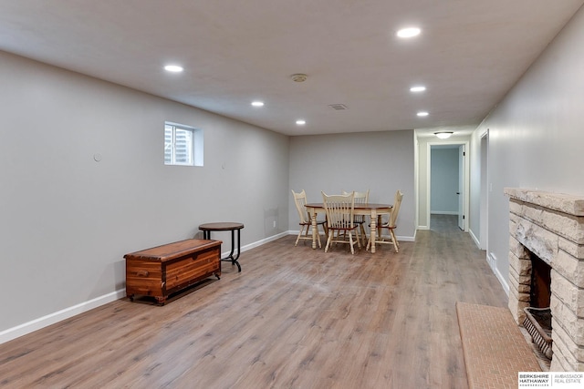 dining room with light wood-type flooring, recessed lighting, baseboards, and a stone fireplace