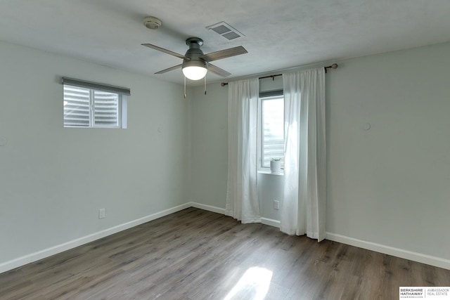 spare room featuring ceiling fan, visible vents, baseboards, and wood finished floors