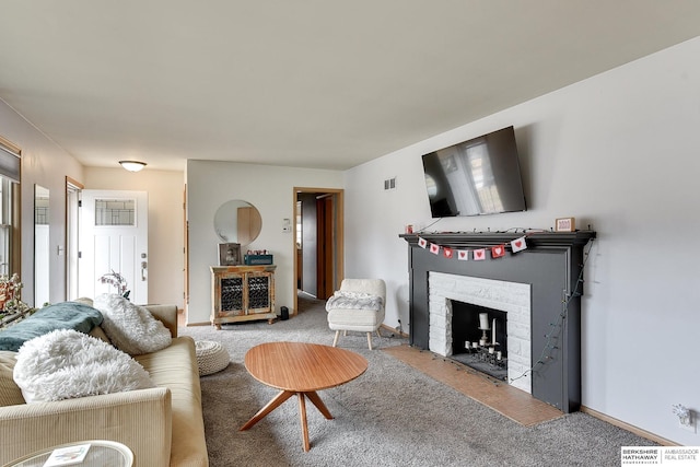 living room with carpet, visible vents, baseboards, and a stone fireplace