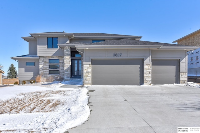 prairie-style home featuring driveway, stone siding, and an attached garage