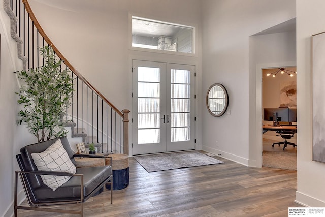 entryway featuring a towering ceiling, baseboards, wood finished floors, and french doors