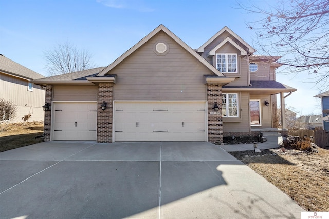 traditional-style home featuring a garage, concrete driveway, brick siding, and roof with shingles