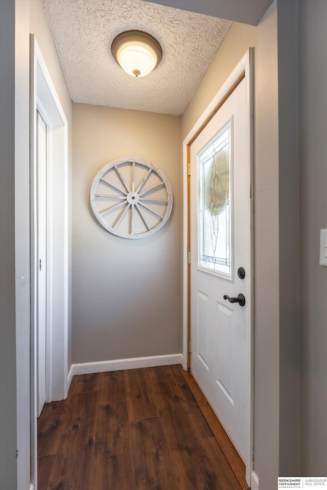 doorway featuring a textured ceiling, baseboards, and wood finished floors