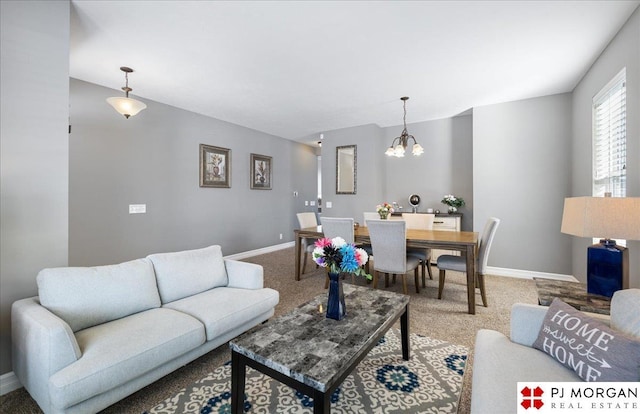 living room with a chandelier, carpet, and baseboards