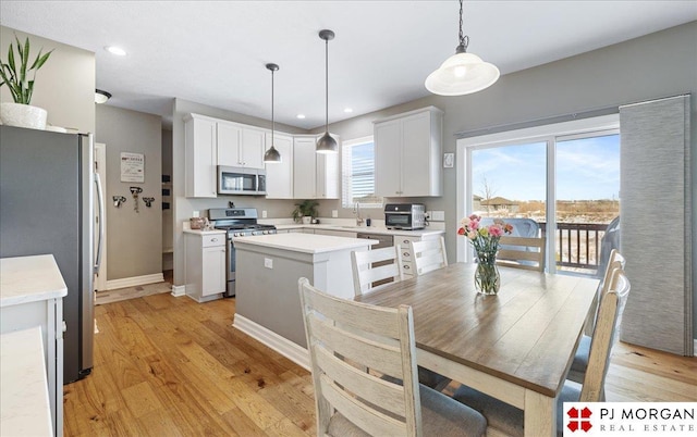 10211 Rosewater Pkwy, Bennington, NE 68007 - kitchen with light countertops, appliances with stainless steel finishes, light wood-style floors, white cabinets, and a kitchen island