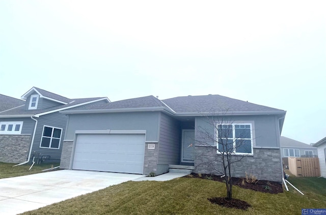 view of front of house with roof with shingles, a front yard, a garage, stone siding, and driveway