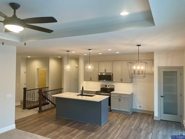 kitchen with stainless steel appliances, a tray ceiling, a sink, and decorative backsplash