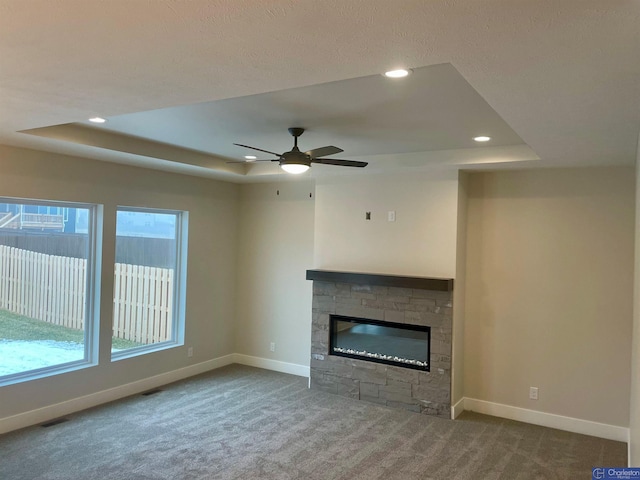 unfurnished living room with carpet floors, a fireplace, and a raised ceiling