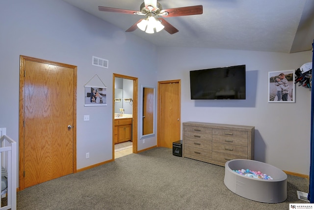 bedroom featuring connected bathroom, a sink, visible vents, vaulted ceiling, and carpet