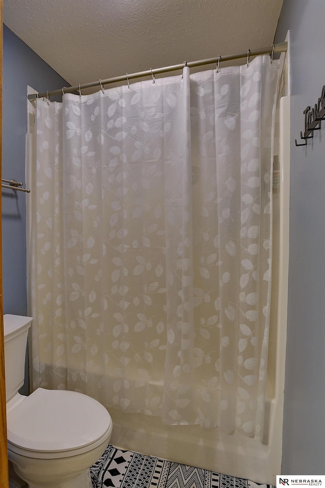 bathroom with toilet, curtained shower, and a textured ceiling