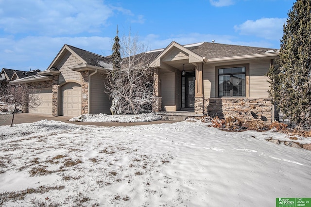 view of front of house with stone siding, driveway, roof with shingles, and an attached garage