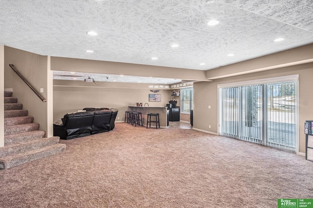 carpeted living room featuring a bar, stairs, a healthy amount of sunlight, and a textured ceiling