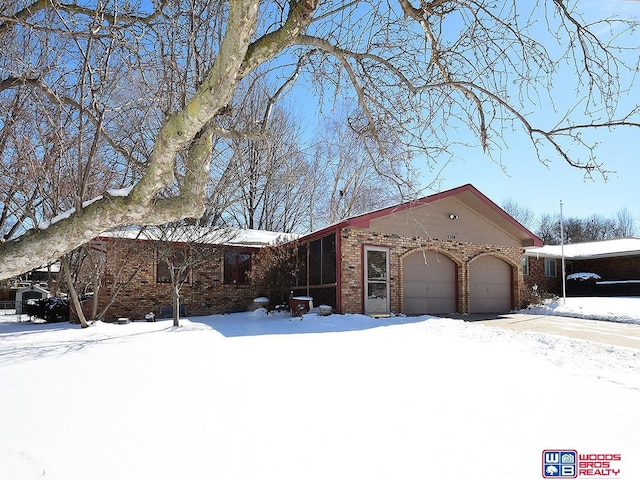 view of front of house with a garage, a sunroom, and brick siding