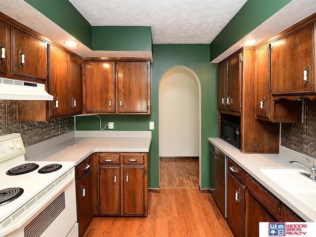 kitchen featuring white electric range oven, arched walkways, under cabinet range hood, black microwave, and a sink