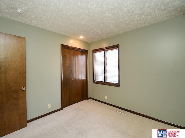 unfurnished bedroom with visible vents, baseboards, a closet, and light colored carpet
