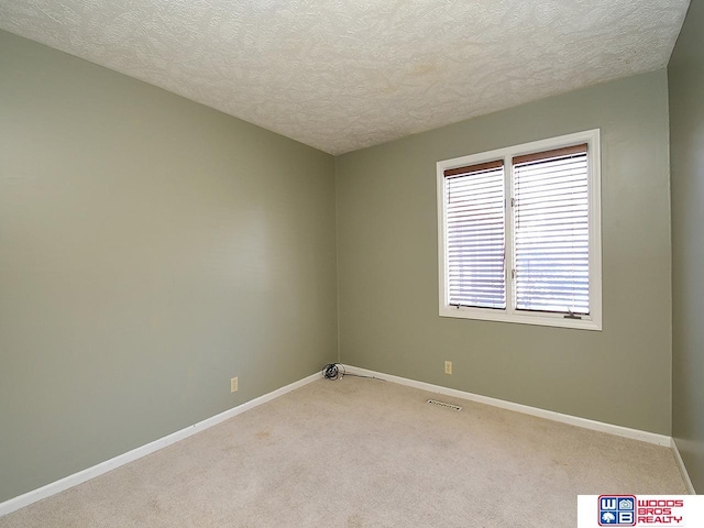 empty room with baseboards, a textured ceiling, and light colored carpet