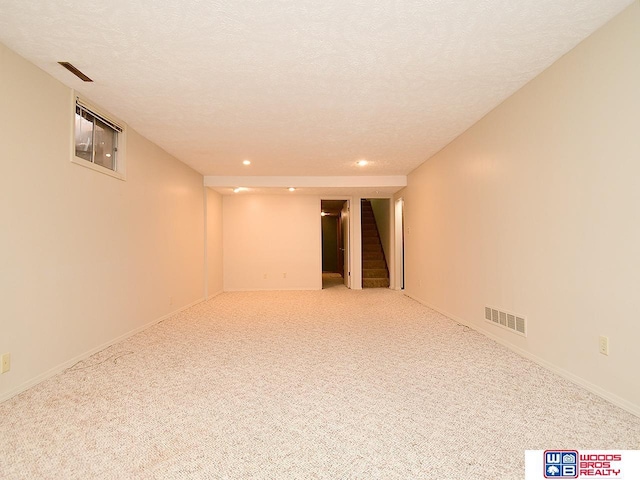 carpeted empty room with a textured ceiling, stairway, visible vents, and recessed lighting