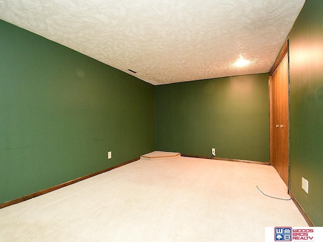 carpeted spare room featuring visible vents, baseboards, and a textured ceiling