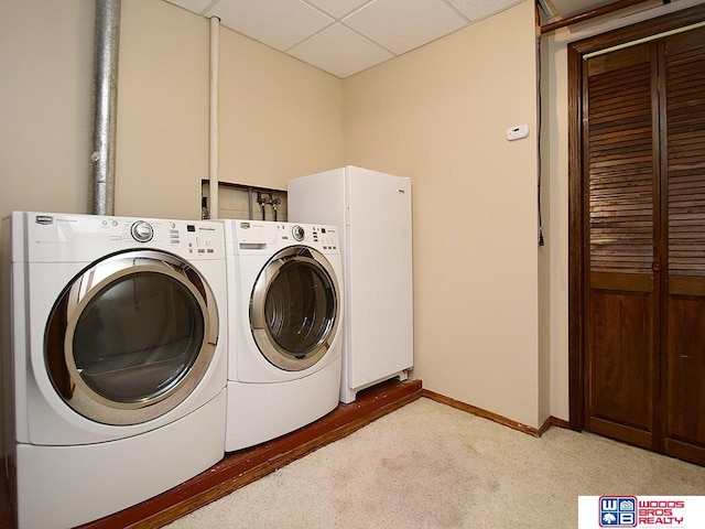 laundry room with washer and dryer, laundry area, light colored carpet, and baseboards