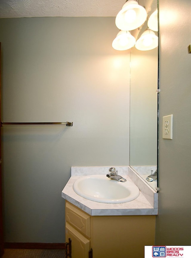 bathroom with baseboards, a textured ceiling, and vanity