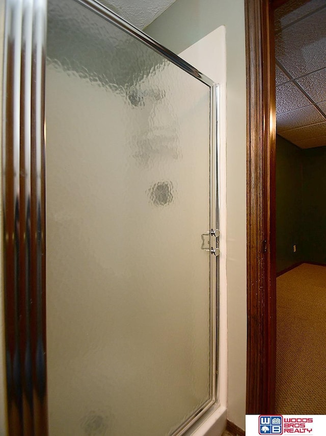 full bath with a paneled ceiling and a shower stall