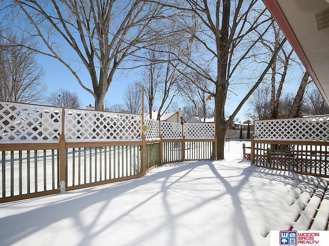 snow covered deck featuring visible vents and fence