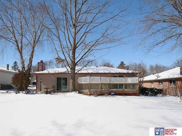 snow covered property featuring a chimney and a wooden deck