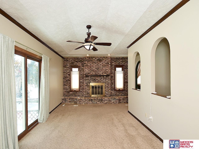 unfurnished living room featuring light carpet, brick wall, ceiling fan, ornamental molding, and a textured ceiling