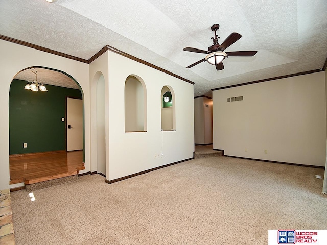spare room featuring a textured ceiling, ceiling fan with notable chandelier, light carpet, visible vents, and ornamental molding