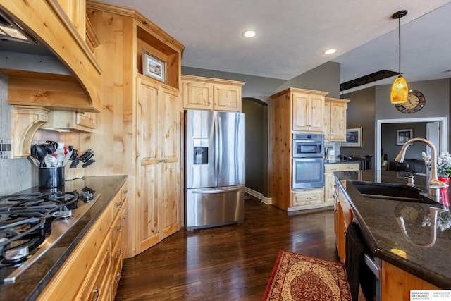 kitchen featuring dark wood-style floors, arched walkways, appliances with stainless steel finishes, light brown cabinets, and a sink