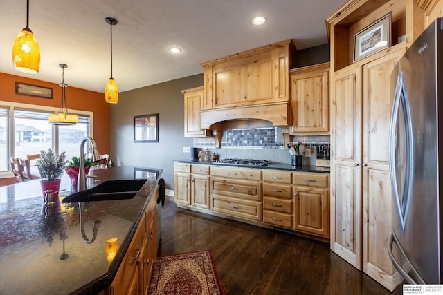 kitchen featuring dark wood-style floors, a sink, stainless steel appliances, light brown cabinetry, and backsplash