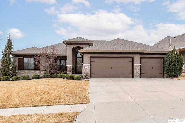 prairie-style house with stucco siding, concrete driveway, an attached garage, stone siding, and a front lawn